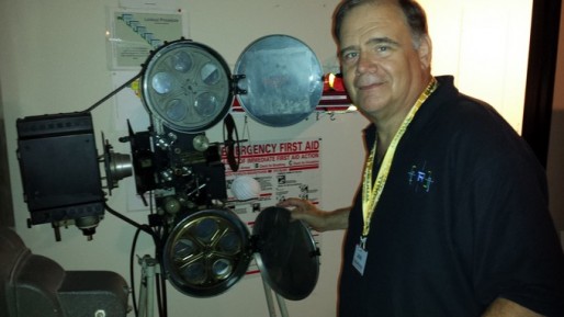 Projectionist Lou DiCrescenzo next to one of his beloved vintage projectors